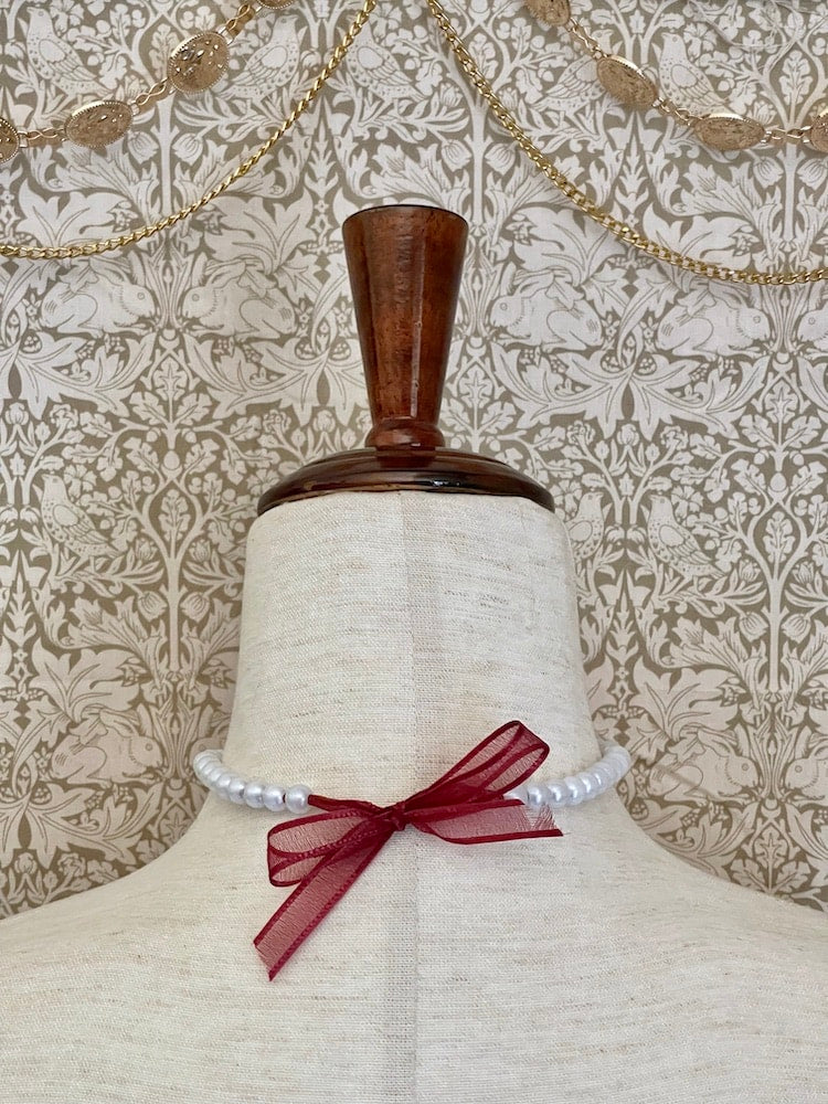 A Handmade Historically Inspired Victorian Pearl Beaded Ribbon Choker Necklace in Burgundy on a mannequin.