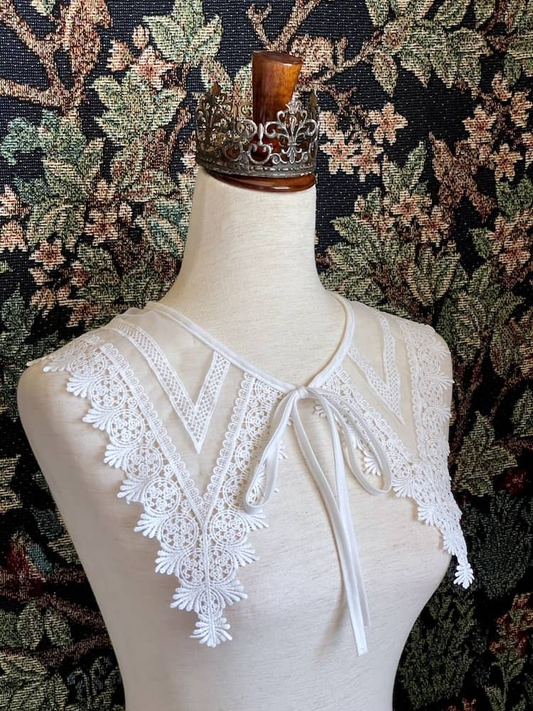 A Historically Inspired Dutch Republic Baroque Era White Venetian Lace Dagger Collar, detachable, with bow closure, on a mannequin.