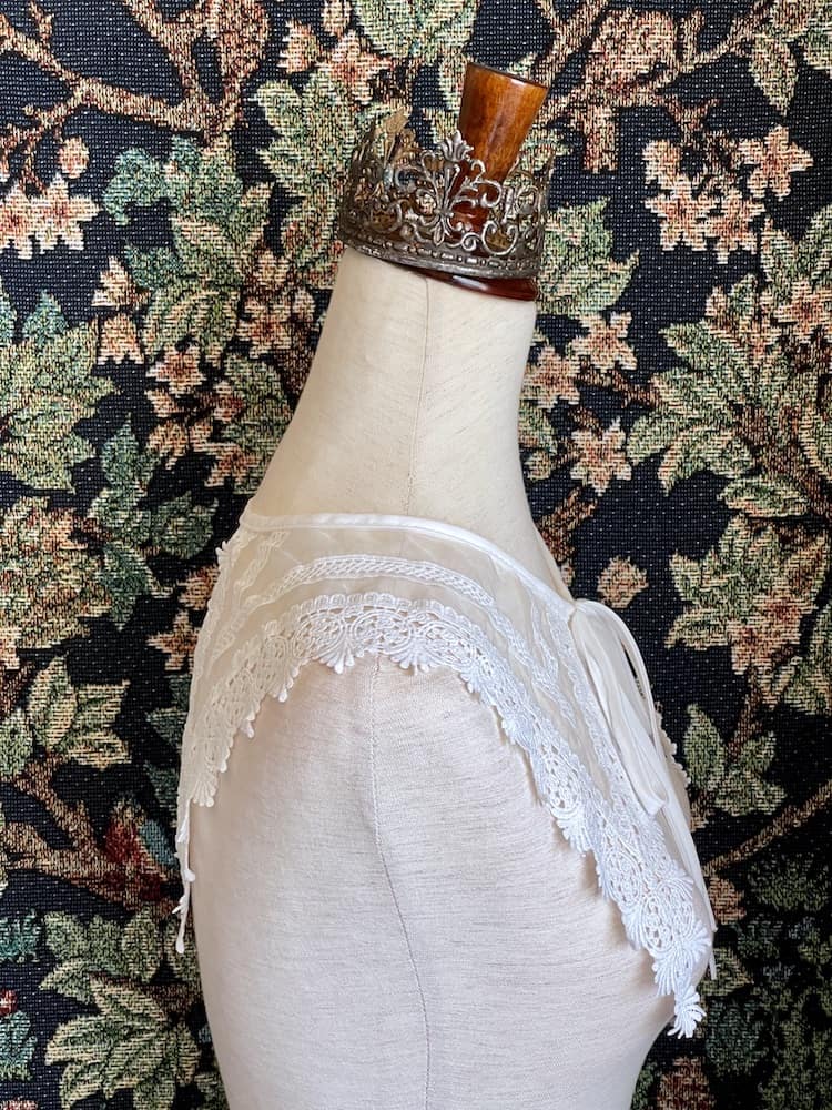A Historically Inspired Dutch Republic Baroque Era White Venetian Lace Dagger Collar, detachable, with bow closure, on a mannequin.