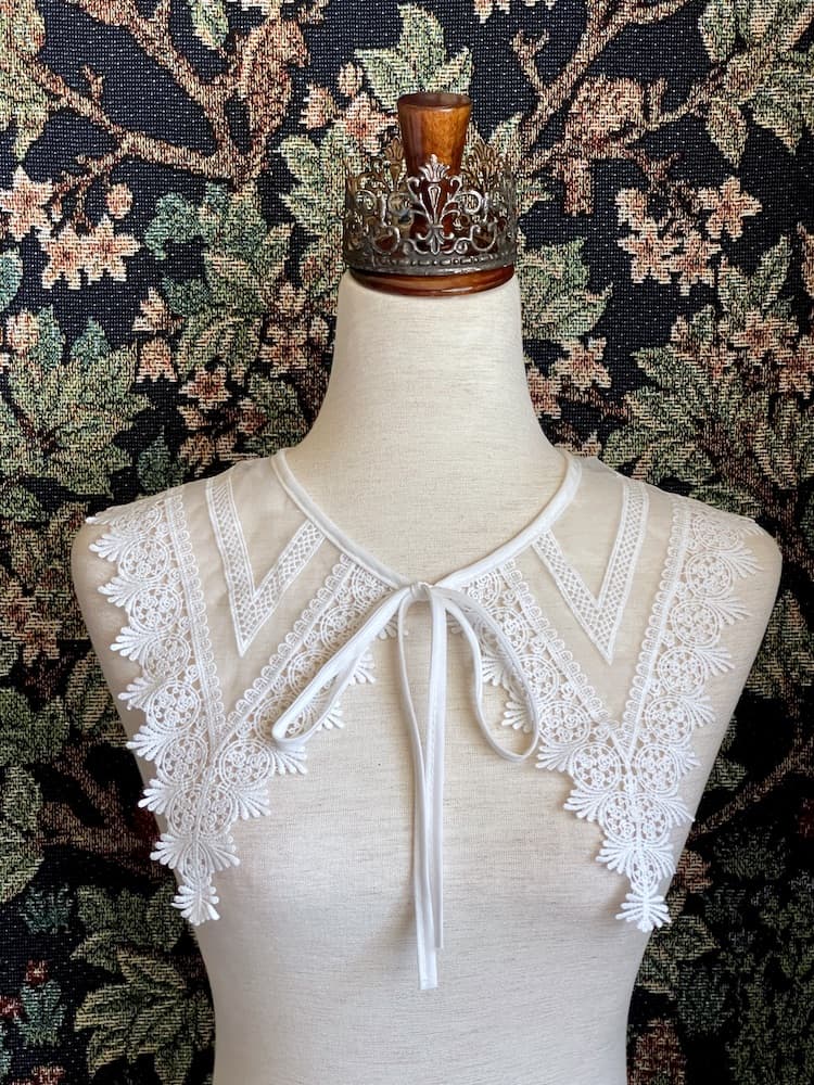 A Historically Inspired Dutch Republic Baroque Era White Venetian Lace Dagger Collar, detachable, with bow closure, on a mannequin.