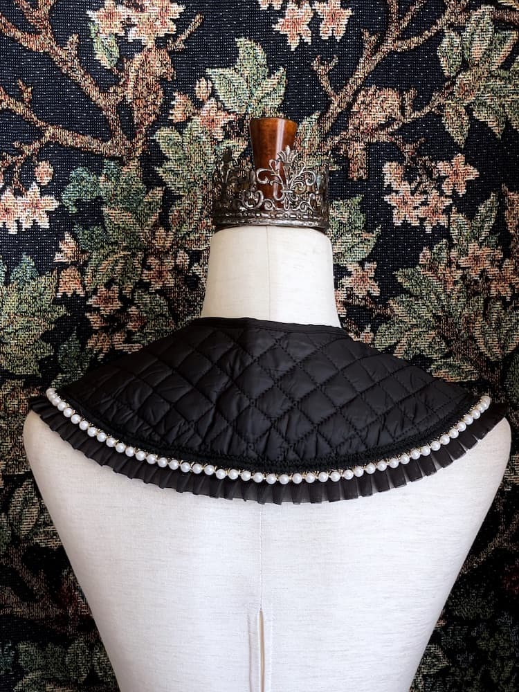 A Historically Inspired Quilted Round Collar with Ruffle & Pearl Trim in Black pictured on a mannequin.