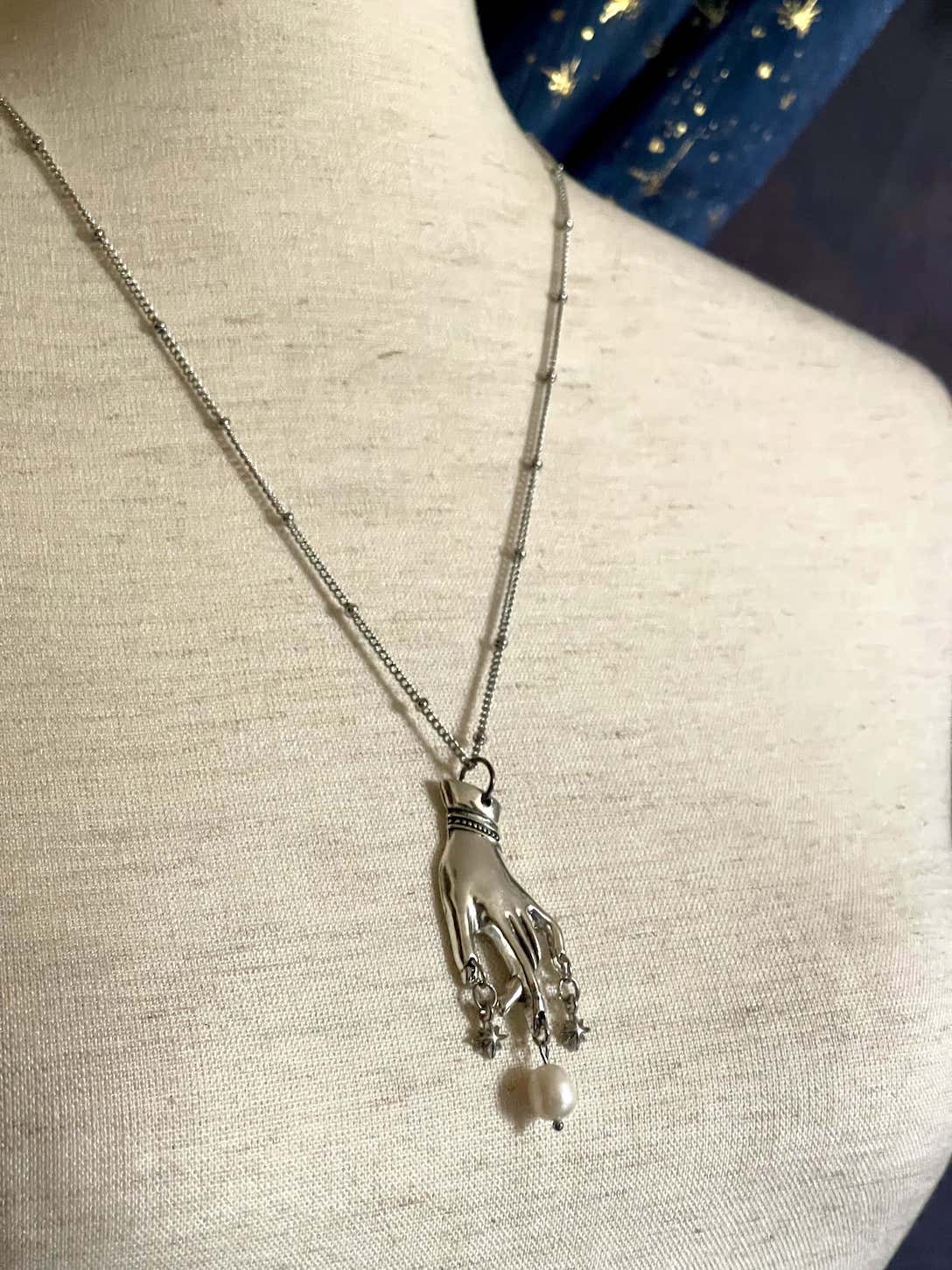 A Handmade Historically Inspired Medieval Hand Pendant Necklace with Real Baroque Pearl Dangle and Celestial Star Charms on a Metal Beaded Chain Necklace in Silver.