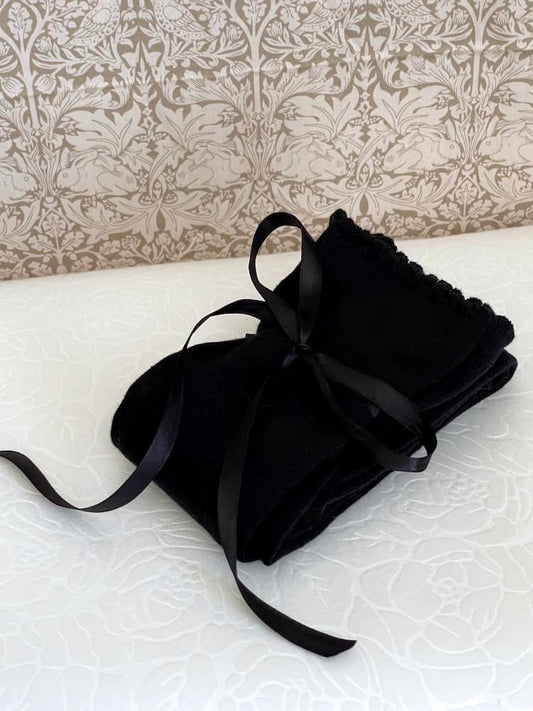 A pair of Historically Inspired Cotton Knee-High Socks with Ribbon Lacing in Black, on a puff. Stockings for any historical era.
