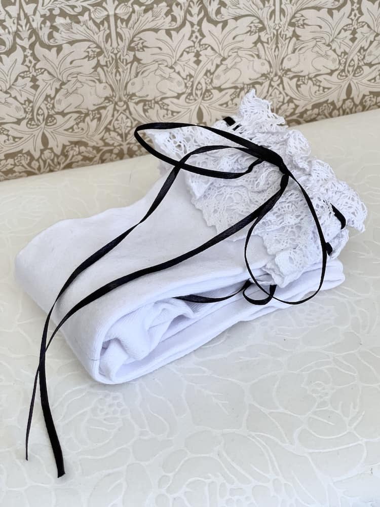 A pair of Historically Inspired Cotton Knee-High Socks with Lace Trim in White & Black. Stockings for any historical era.