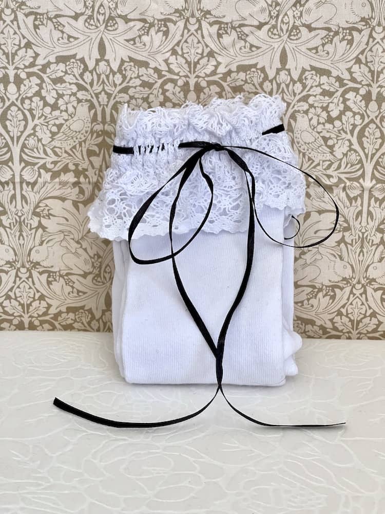 A pair of Historically Inspired Cotton Knee-High Socks with Lace Trim in White & Black. Stockings for any historical era.