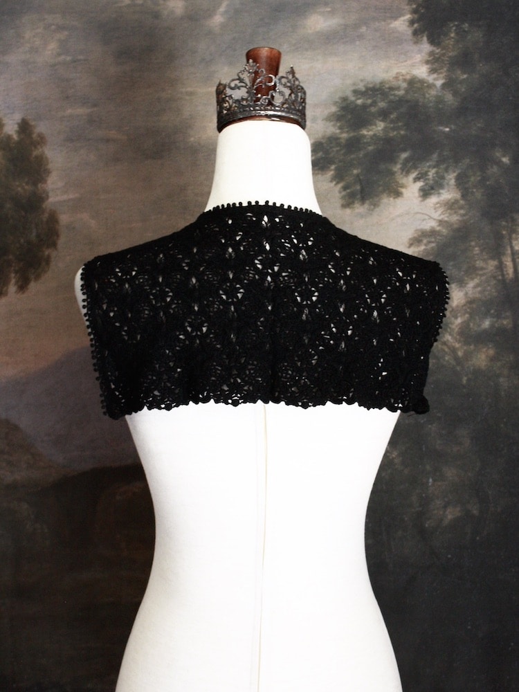 Historically Inspired Floral Crochet Folk Shawl / Capelet in Gothic Black on a mannequin in front of a painting backdrop. Victorian, renaissance, medieval.