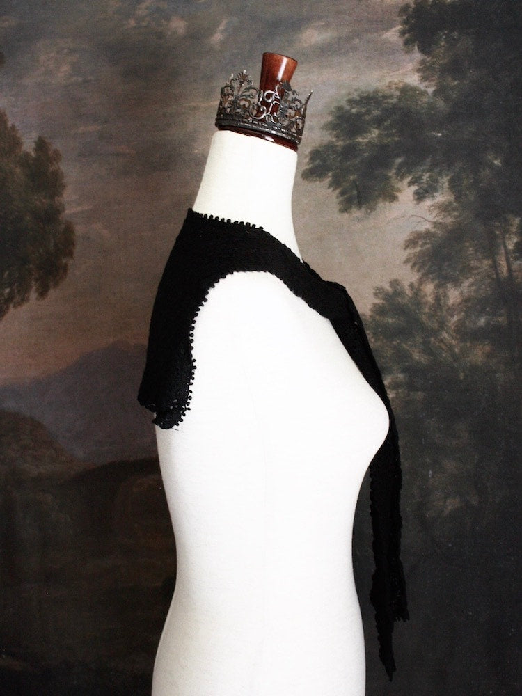 Historically Inspired Floral Crochet Folk Shawl / Capelet in Gothic Black on a mannequin in front of a painting backdrop. Victorian, renaissance, medieval.