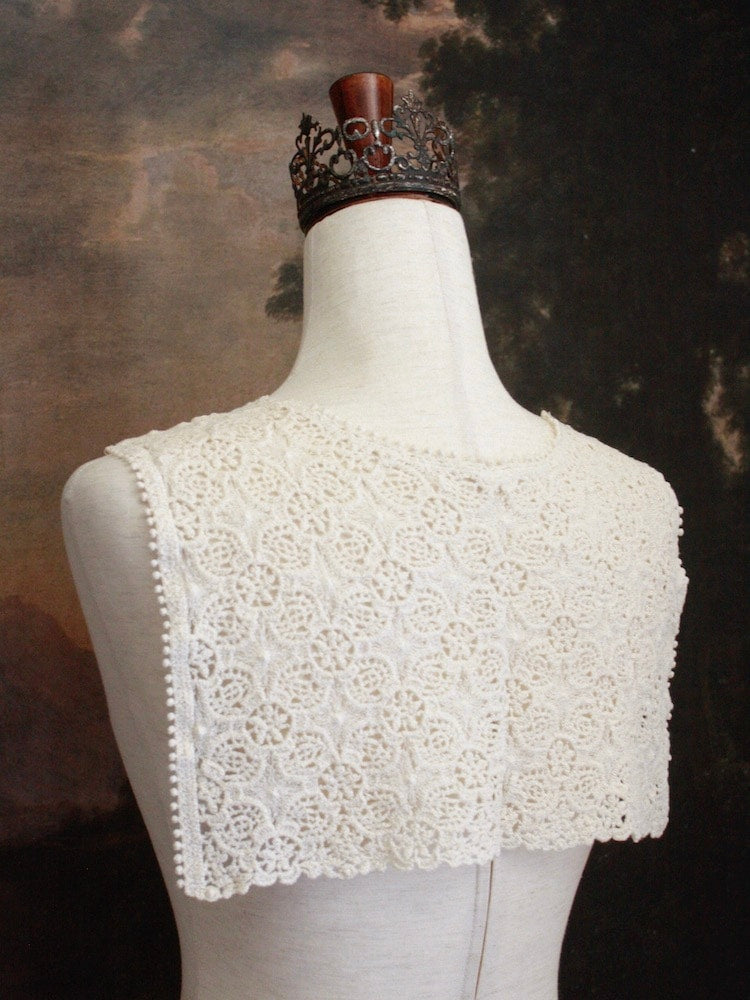 Historically Inspired Floral Crochet Folk Shawl / Capelet in Ivory on a mannequin in front of a painting backdrop. Victorian, renaissance, medieval.