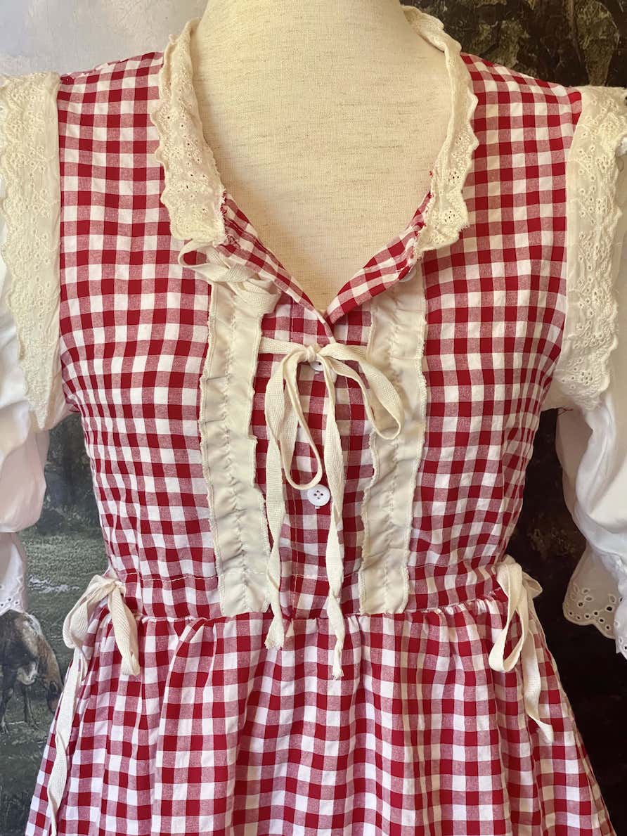 A historically inspired vintage style red and ivory gingham check mini dress with lace trim and ribbon ties.