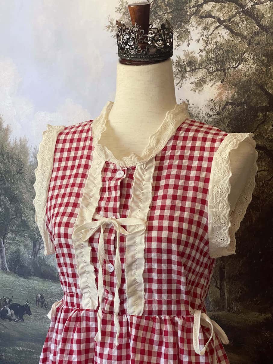 A historically inspired vintage style red and ivory gingham check mini dress with lace trim and ribbon ties.