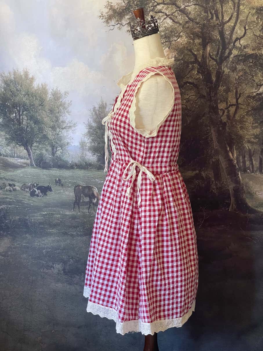 A historically inspired vintage style red and ivory gingham check mini dress with lace trim and ribbon ties.