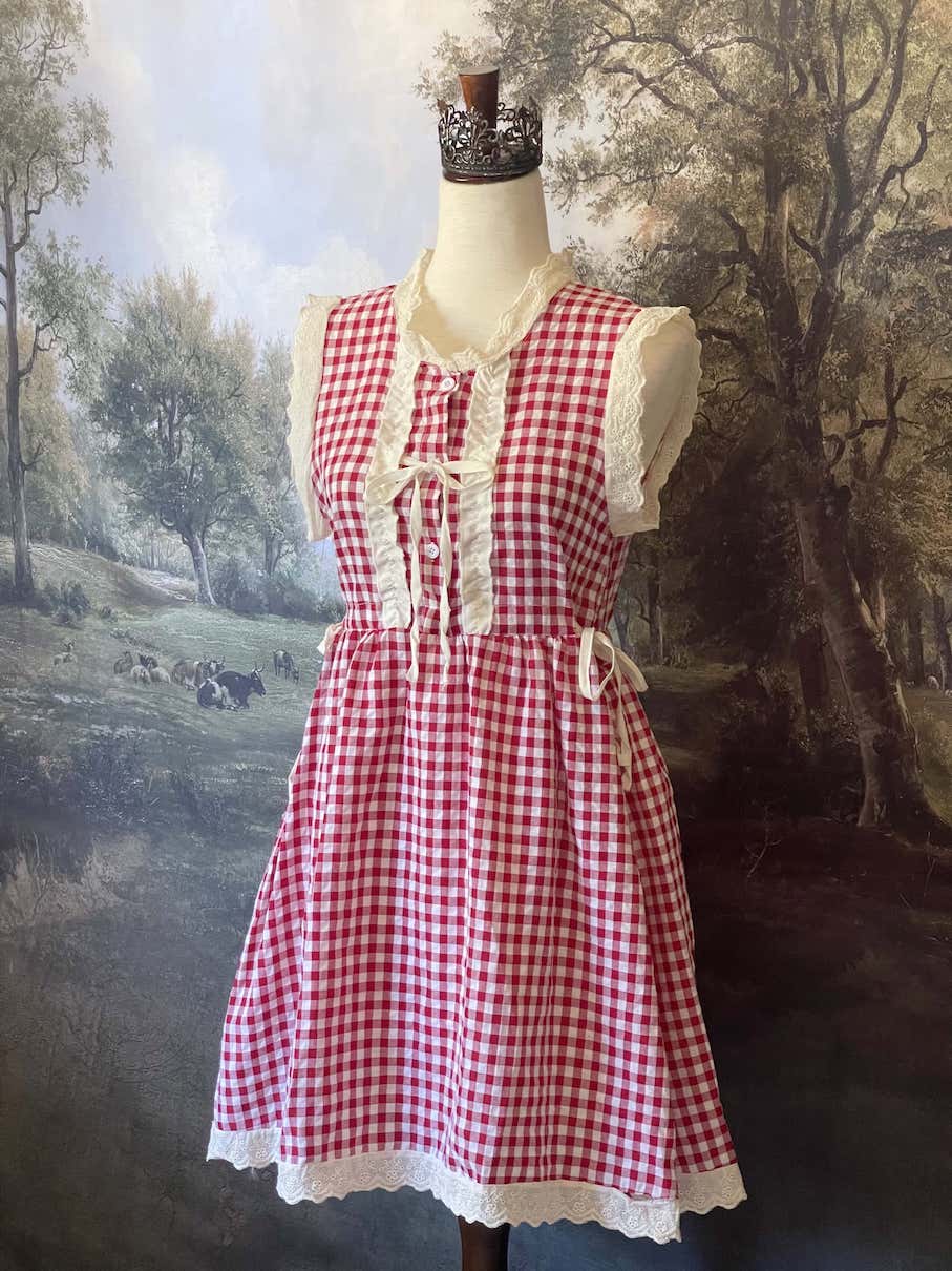 A historically inspired vintage style red and ivory gingham check mini dress with lace trim and ribbon ties.