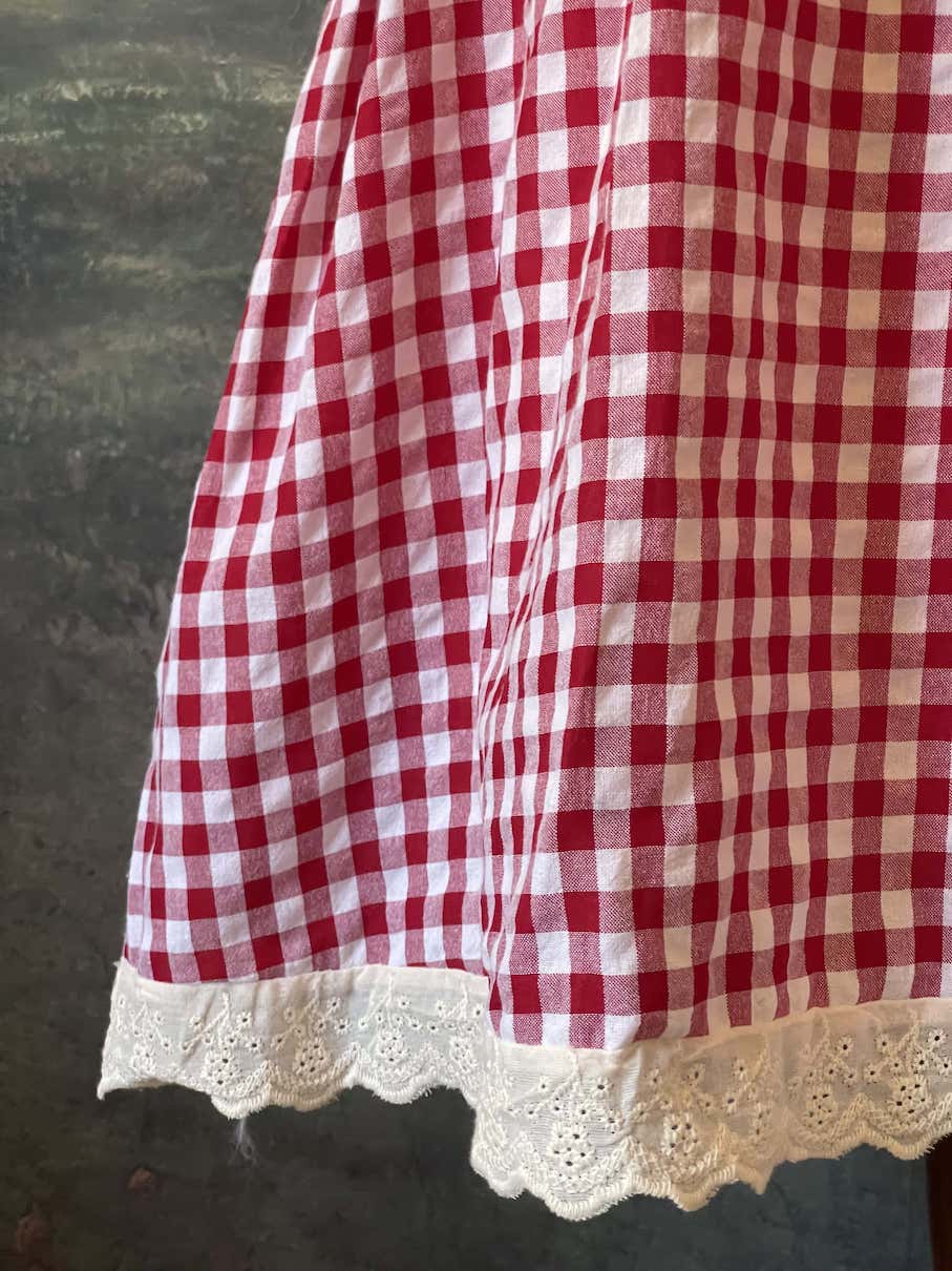 A historically inspired vintage style red and ivory gingham check mini dress with lace trim and ribbon ties.