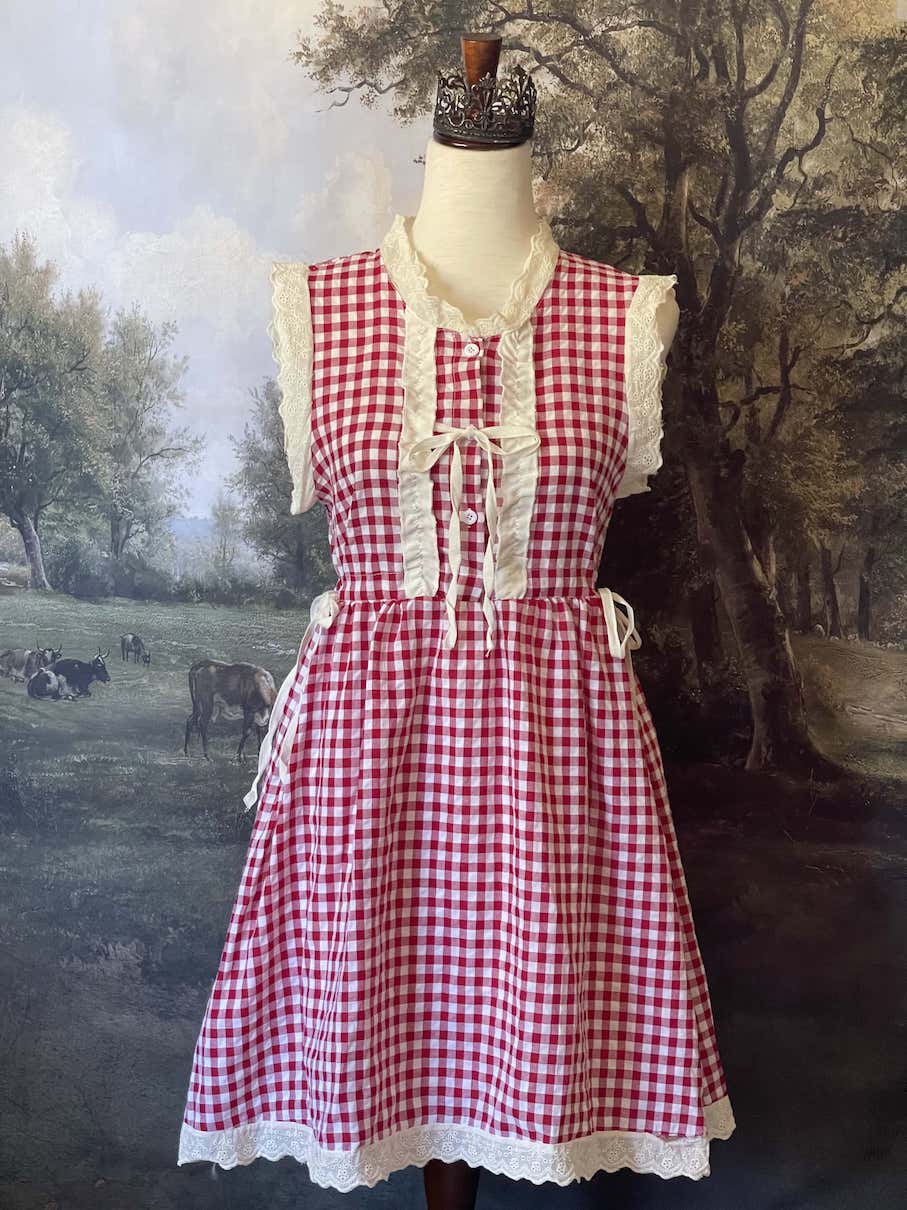 A historically inspired vintage style red and ivory gingham check mini dress with lace trim and ribbon ties.