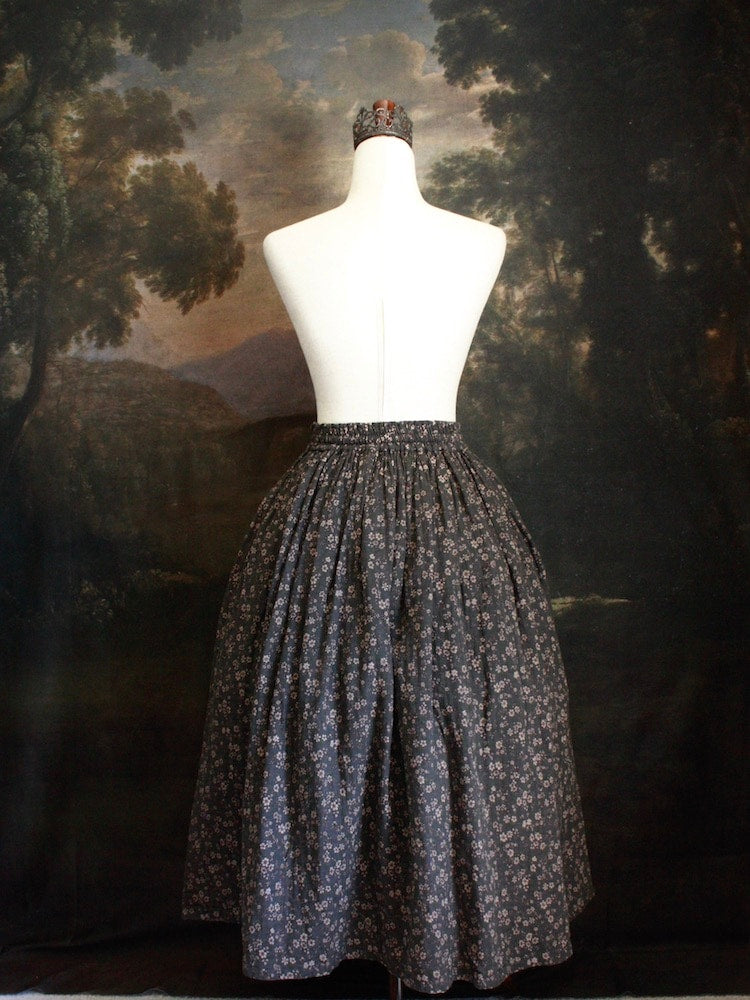Historically Inspired victorian era peasant turn of the century Printed Floral Cotton Maxi Skirt in Dusty Gray-Blue pictured on a mannequin in front of a classical painting.
