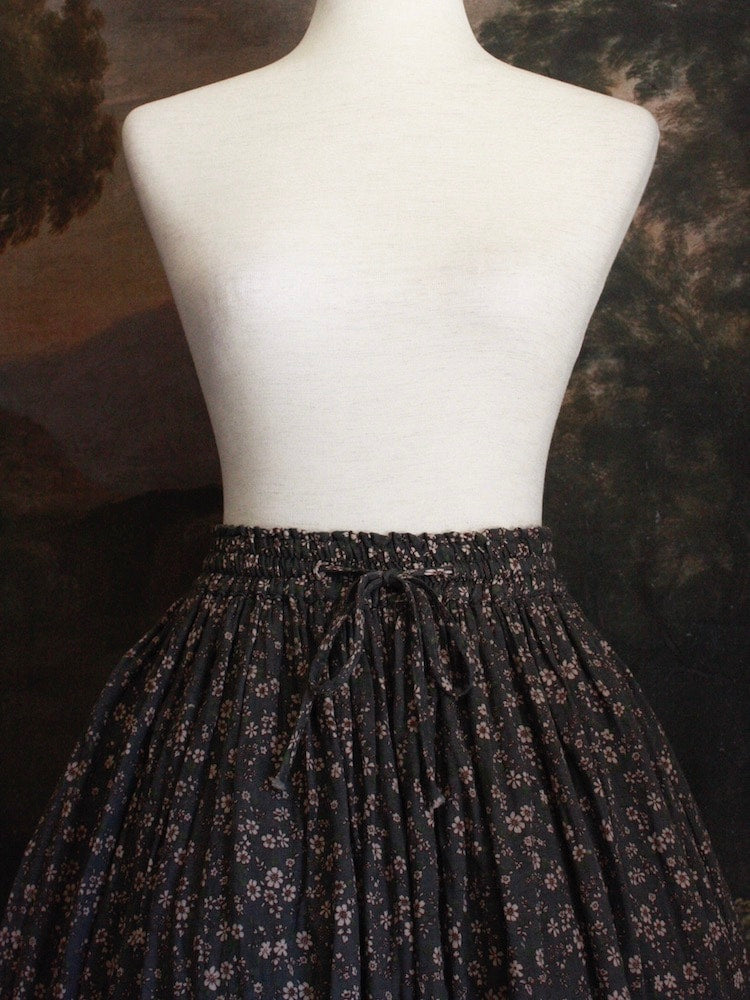 Historically Inspired victorian era peasant turn of the century Printed Floral Cotton Maxi Skirt in Dusty Gray-Blue pictured on a mannequin in front of a classical painting.