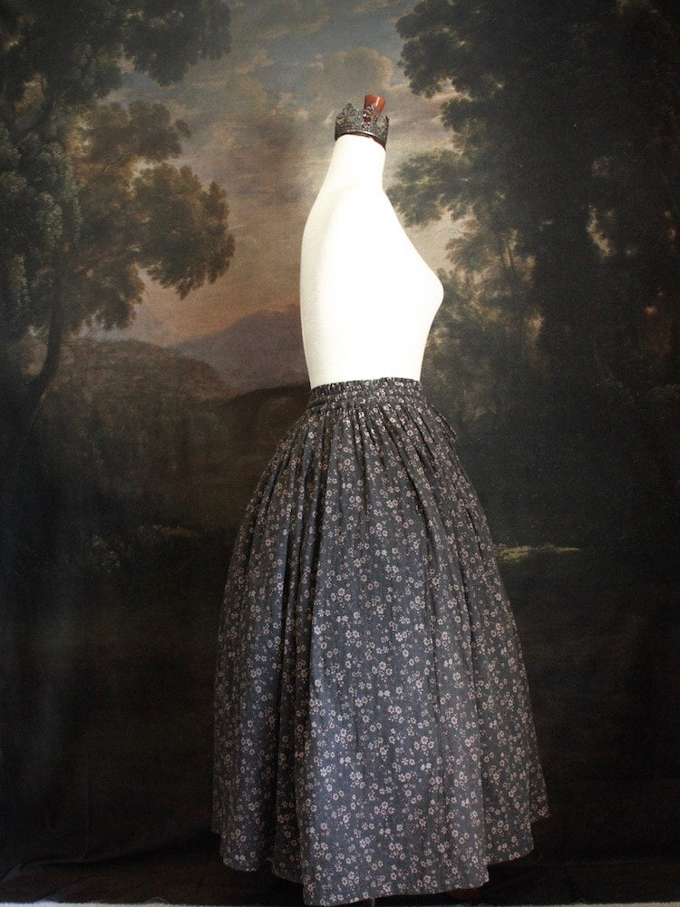 Historically Inspired victorian era peasant turn of the century Printed Floral Cotton Maxi Skirt in Dusty Gray-Blue pictured on a mannequin in front of a classical painting.