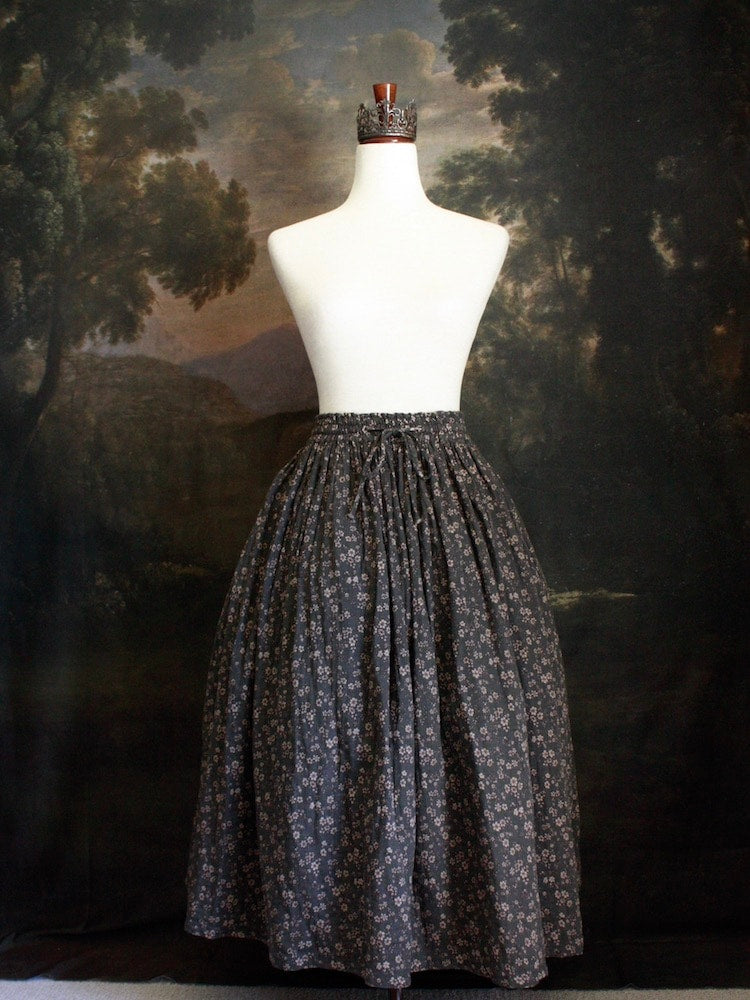Historically Inspired victorian era peasant turn of the century Printed Floral Cotton Maxi Skirt in Dusty Gray-Blue pictured on a mannequin in front of a classical painting.