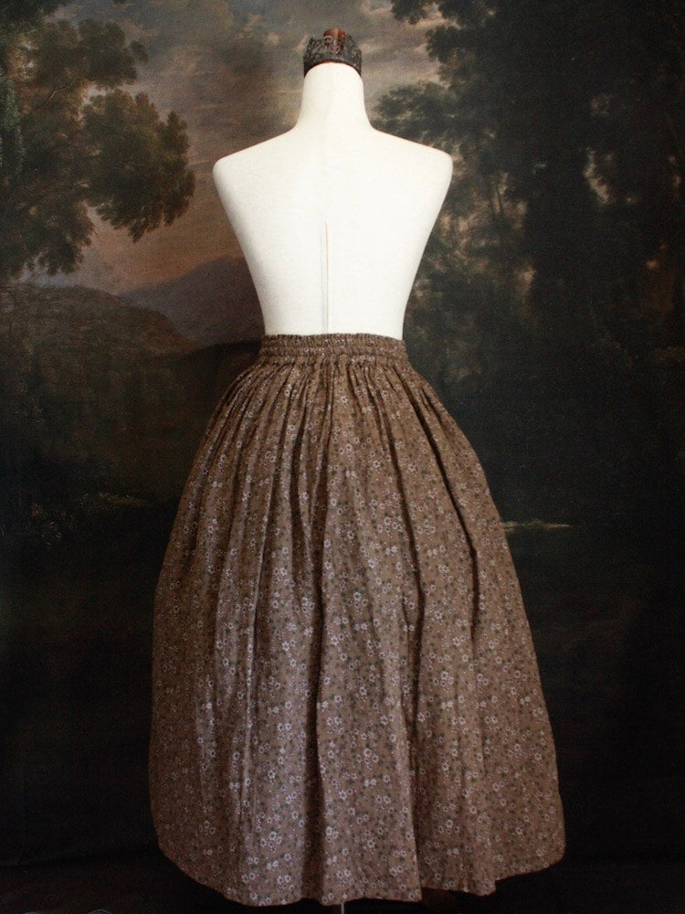 Historically Inspired victorian era peasant turn of the century Printed Floral Cotton Maxi Skirt in Dusty Brown, pictured on a mannequin in front of a classical painting.