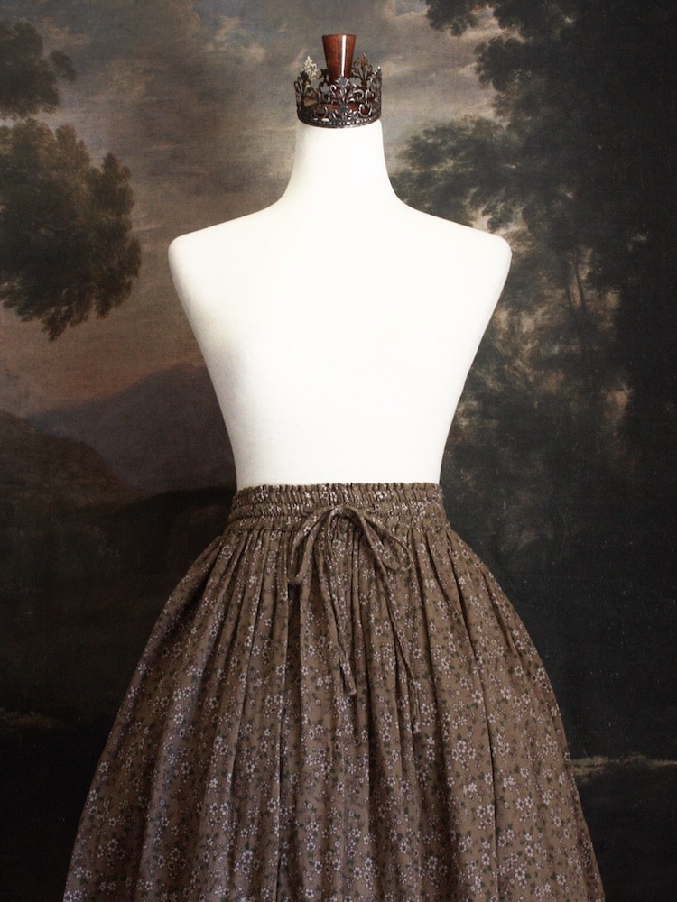 Historically Inspired victorian era peasant turn of the century Printed Floral Cotton Maxi Skirt in Dusty Brown, pictured on a mannequin in front of a classical painting.