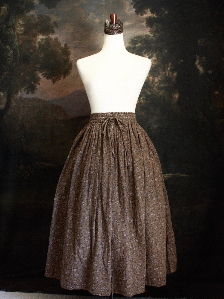 Historically Inspired victorian era peasant turn of the century Printed Floral Cotton Maxi Skirt in Dusty Brown, pictured on a mannequin in front of a classical painting.