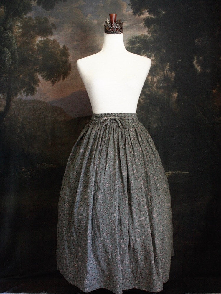 Historically Inspired victorian era peasant turn of the century Printed Floral Cotton Maxi Skirt in Dusty Sage Green pictured on a mannequin in front of a classical painting.