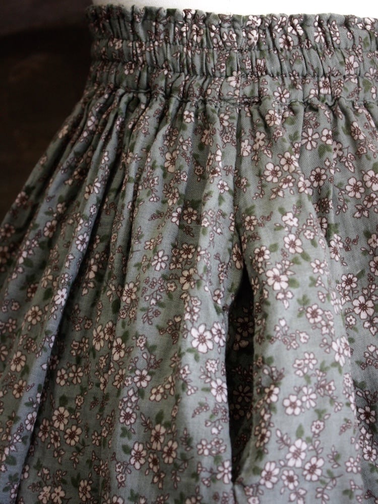 Historically Inspired victorian era peasant turn of the century Printed Floral Cotton Maxi Skirt in Dusty Sage Green pictured on a mannequin in front of a classical painting. Pocket detail.