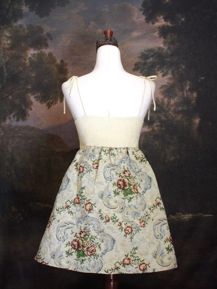 A Historically Inspired Coquette Rococo Baroque Ornate Rose Gobelin Tapestry Mini Dress in front of a historical backdrop.