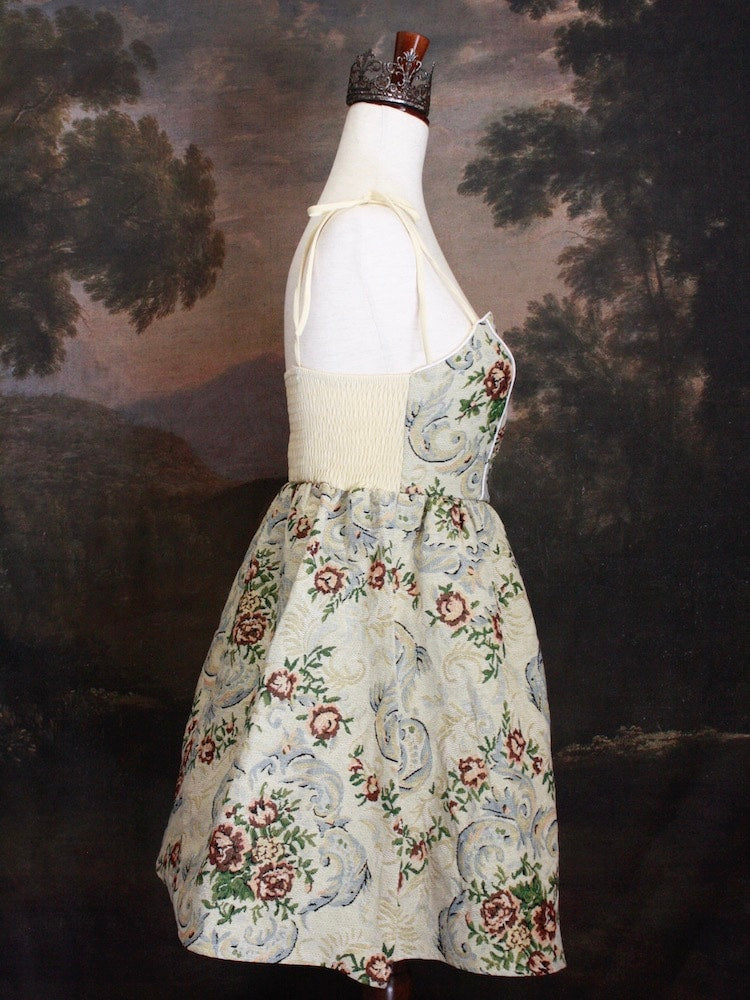 A Historically Inspired Coquette Rococo Baroque Ornate Rose Gobelin Tapestry Mini Dress in front of a historical backdrop.