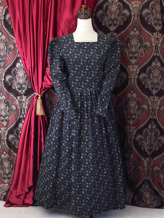 A vintage Laura Ashley historically inspired floral print corduroy prairie dress gown with puff sleeves and a square neckline is pictured in front of an ornate backdrop.