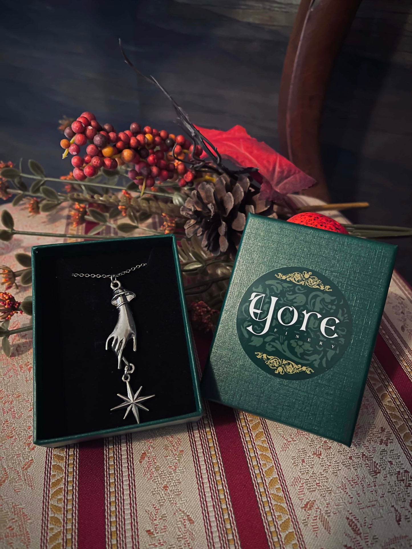 A green, red, and white holiday gift box for historical jewelry with the Yore Logo and a red and white candy-striped bow.