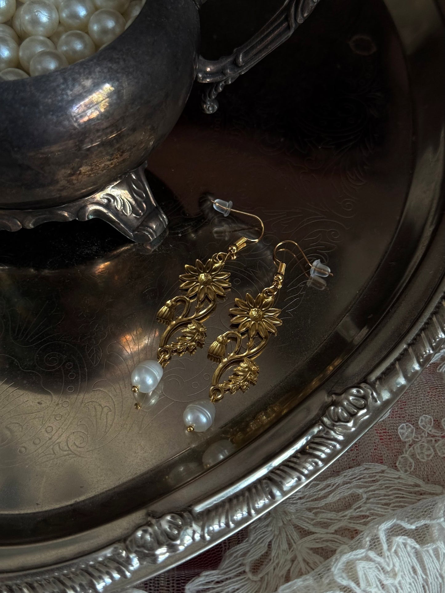 Historically inspired gold toned medieval wildflower daisy earrings with pearl dangle drops, displayed on an antique silver dish.