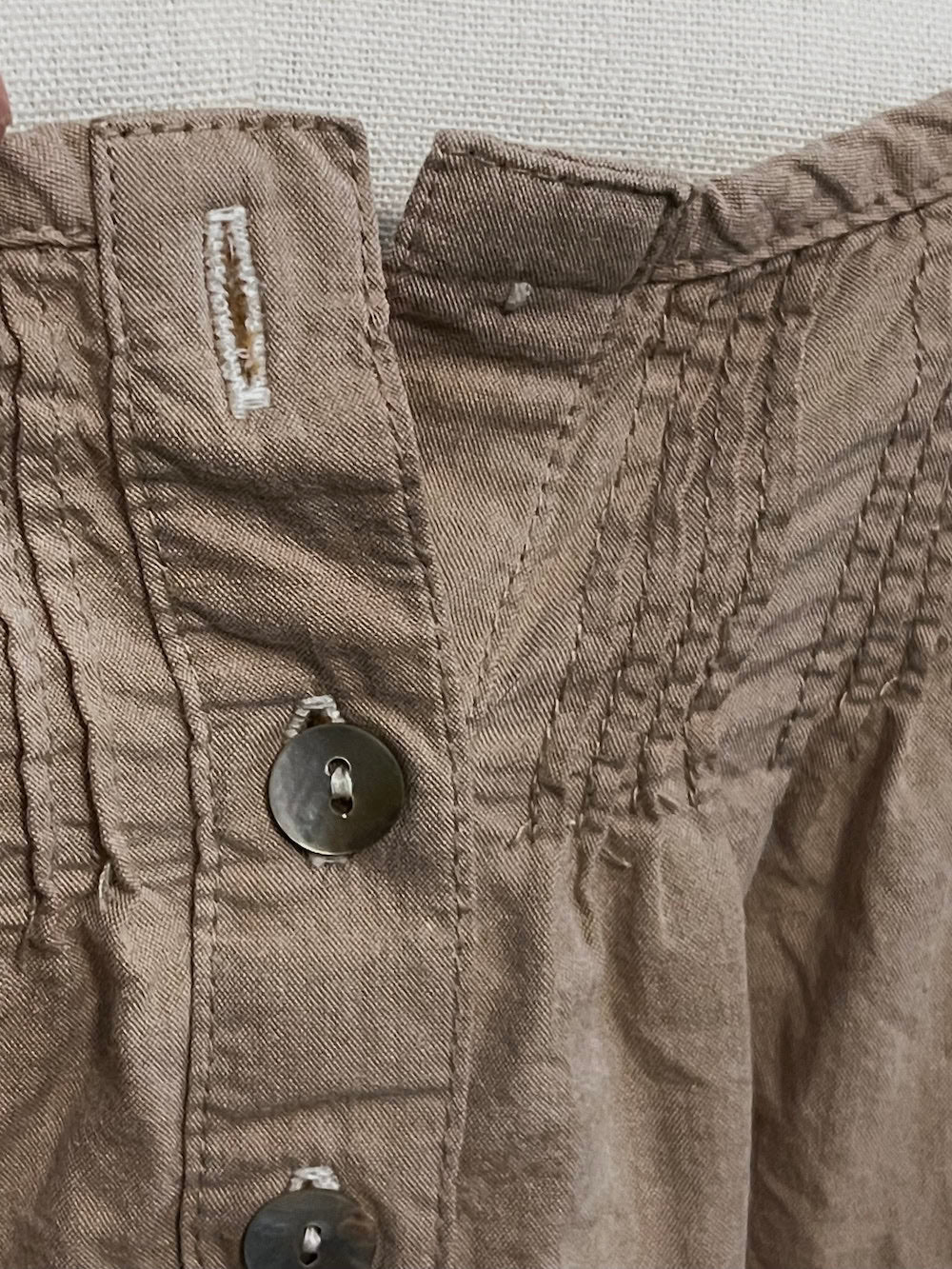 Close-up of a brown fabric with stitching details and a button.