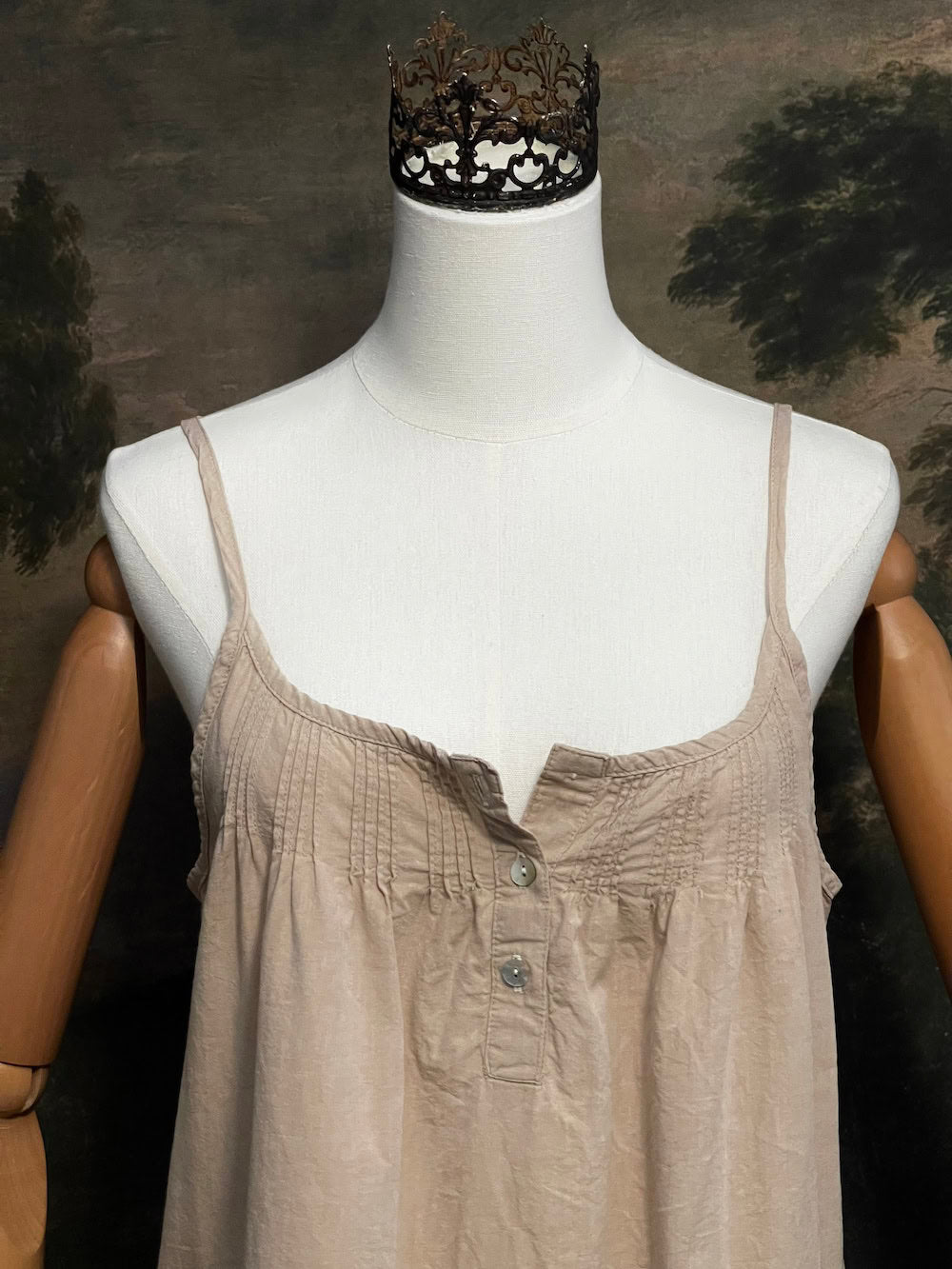A HISTORICALLY INSPIRED Beige slip chemise dress on a mannequin against a historical painting backdrop.