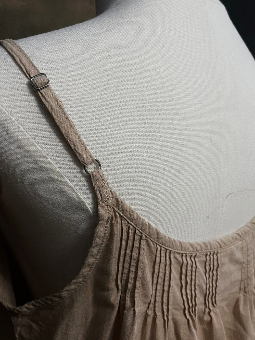 Pleated details on a beige historically inspired slip chemise dress