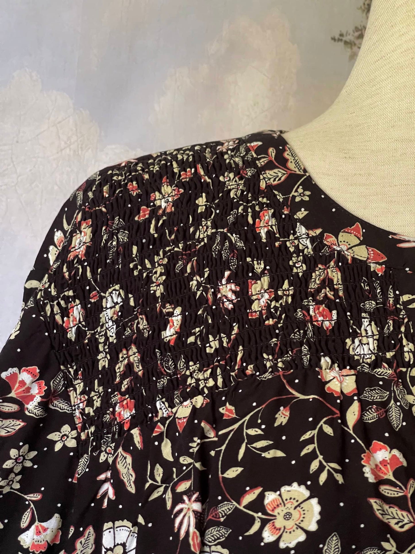 A Medieval Inspired Dark Botanical Print Blouse with Bishop Sleeves on a mannequin in front of a forested painting backdrop.