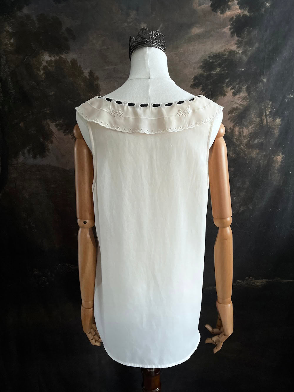 off-white vintage style peter-pan collar blouse with black ribbon bow details on a mannequin against a dark art history background