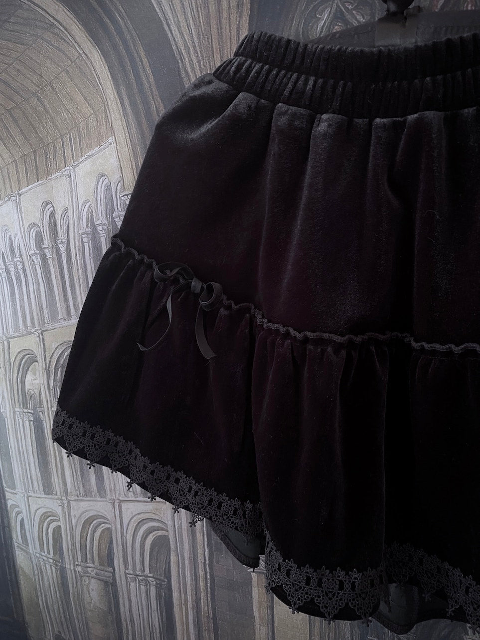 A Historically Inspired Renaissance and Medieval Style Gothic Lace-Trimmed Velvet Mini Skirt in Black with Bow appliques.