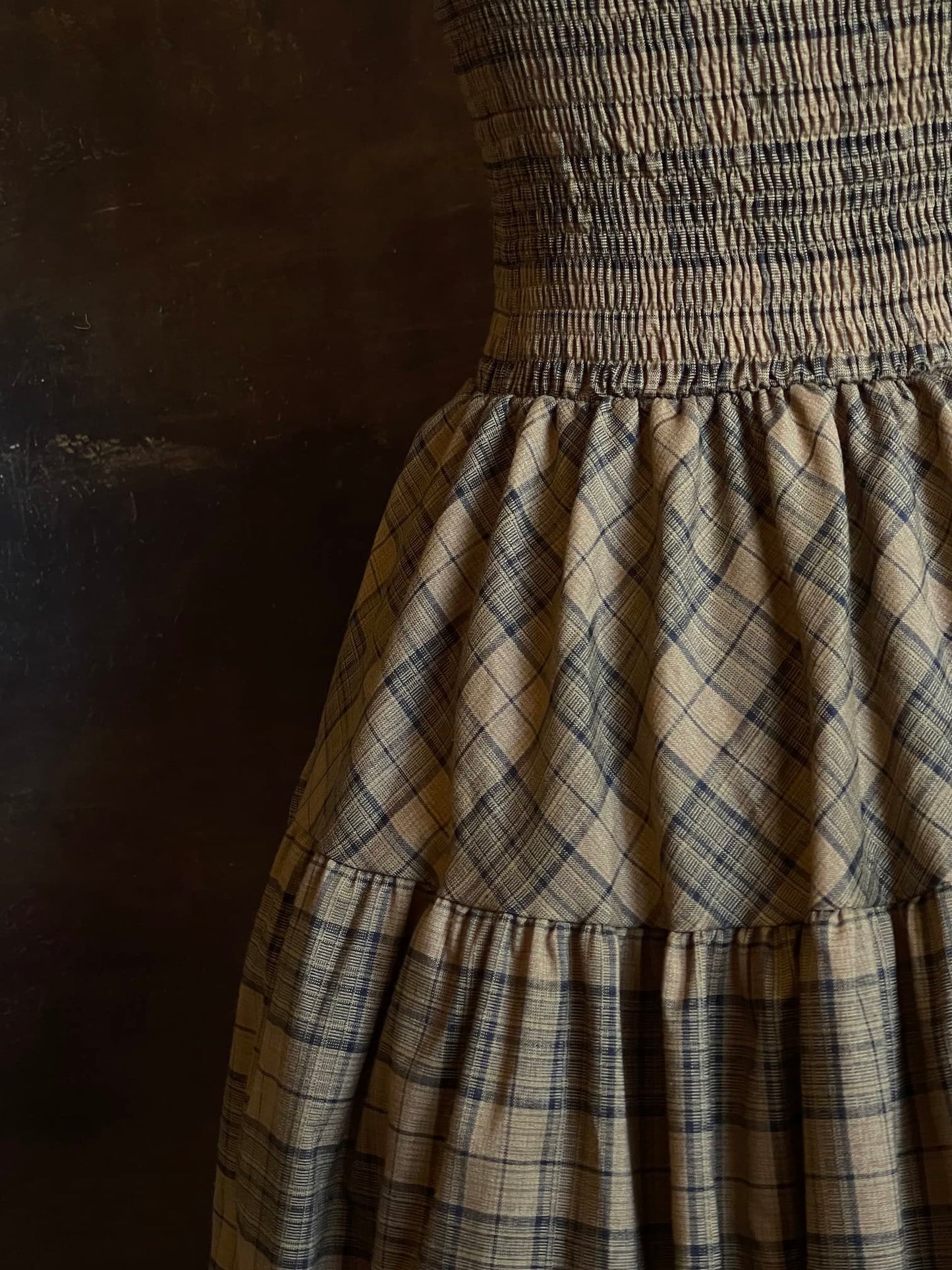 An early medieval era, Celtic historically inspired olive green tartan plaid smocked maxi dress with tiered skirt pictured on a mannequin. Cotton Detail.