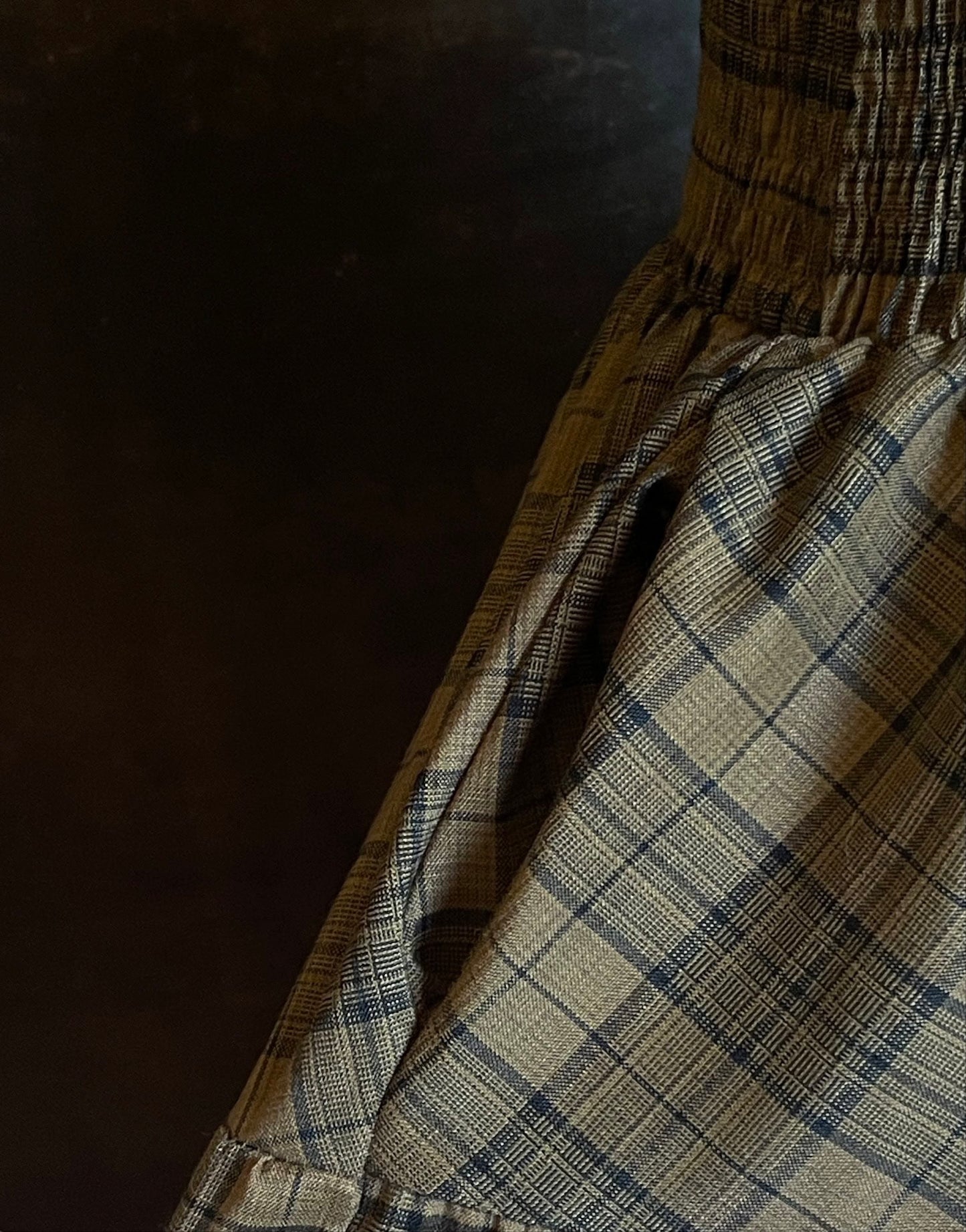 An early medieval era, Celtic historically inspired olive green tartan plaid smocked maxi dress with tiered skirt pictured on a mannequin. Pocket detail.