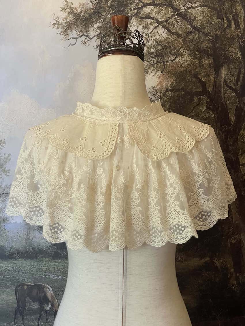 A Historically inspired edwardian victorian regency and rococo style lace capelet shawl in ivory with bow and floral embroidered details.