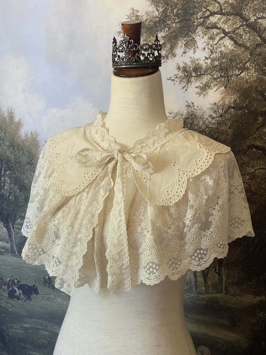 A Historically inspired edwardian victorian regency and rococo style lace capelet shawl in ivory with bow and floral embroidered details.