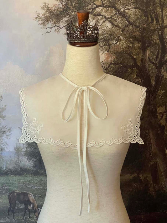 A Historically inspired edwardian and victorian and baroque era removeable collar shawl with floral embroidery and a scalloped hem in white.