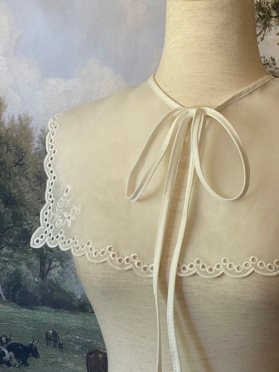 A Historically inspired edwardian and victorian and baroque era removeable collar shawl with floral embroidery and a scalloped hem in white.