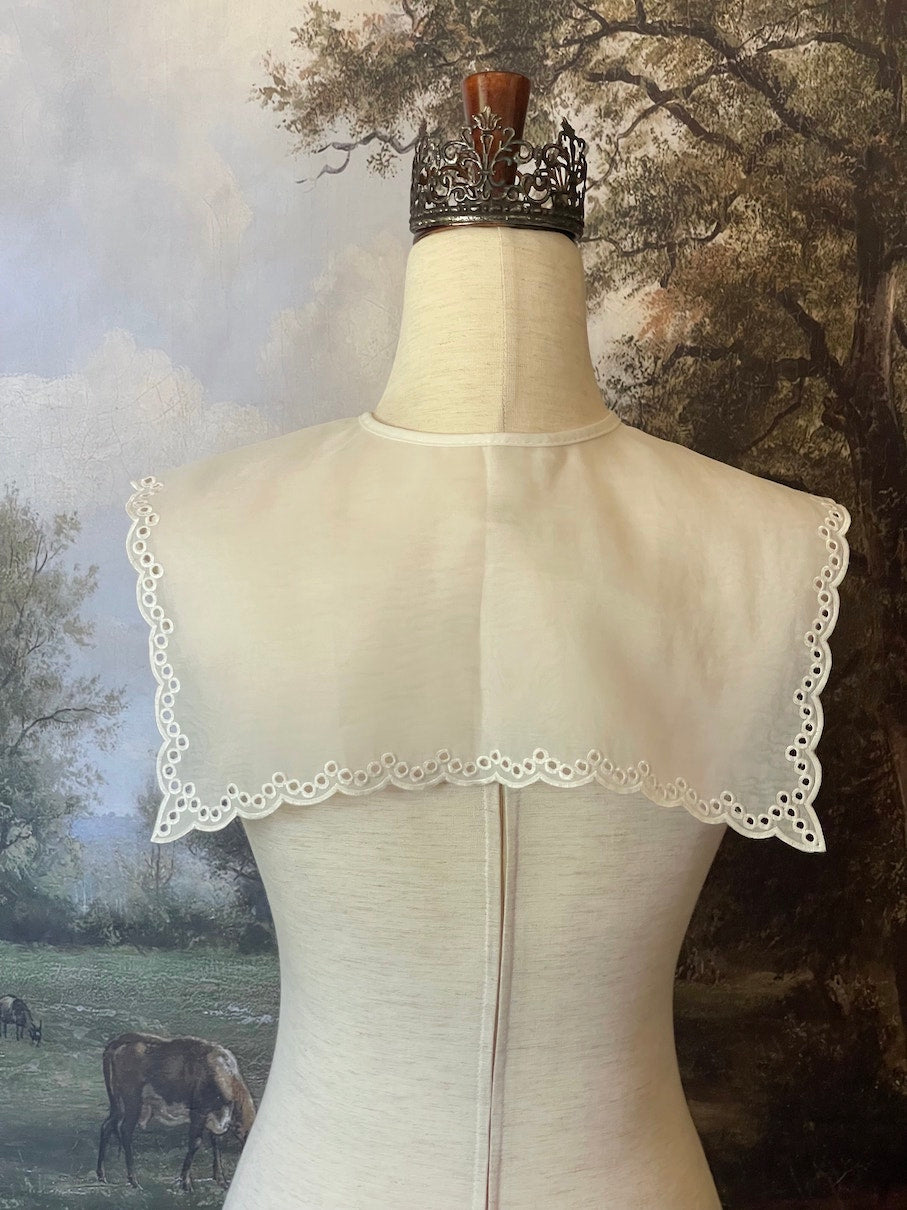 A Historically inspired edwardian and victorian and baroque era removeable collar shawl with floral embroidery and a scalloped hem in white.