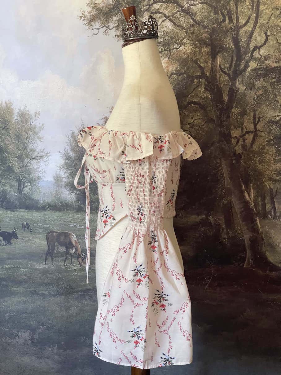 A historically inspired off-shoulder ruffle neckline floral print blouse with bell sleeves and a structured corset-like bodice.