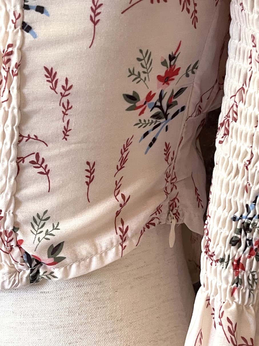 A historically inspired off-shoulder ruffle neckline floral print blouse with bell sleeves and a structured corset-like bodice.