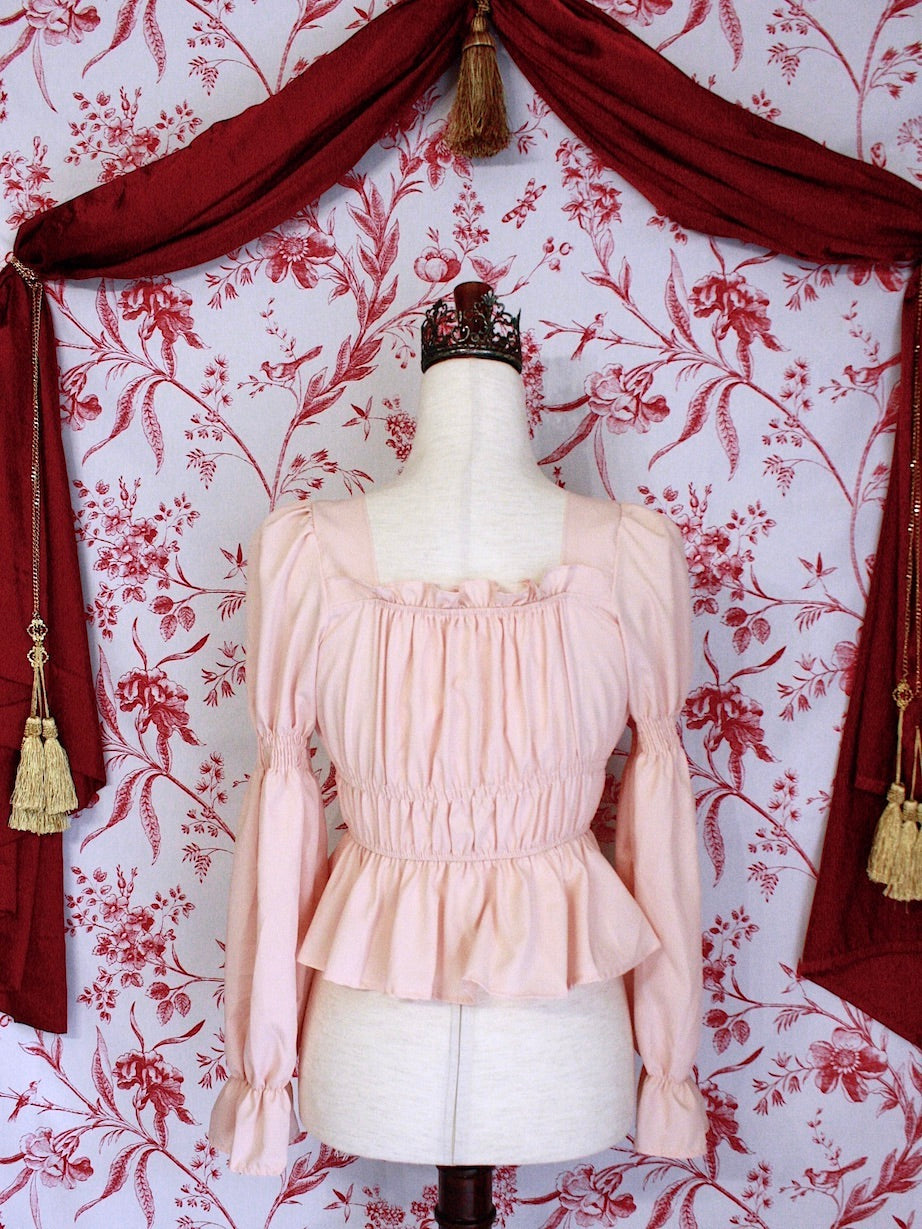 Historically Inspired Renaissance Smocked Blouse with Juliet Puff Sleeves in Peachy Pink, in front of a toile backdrop.