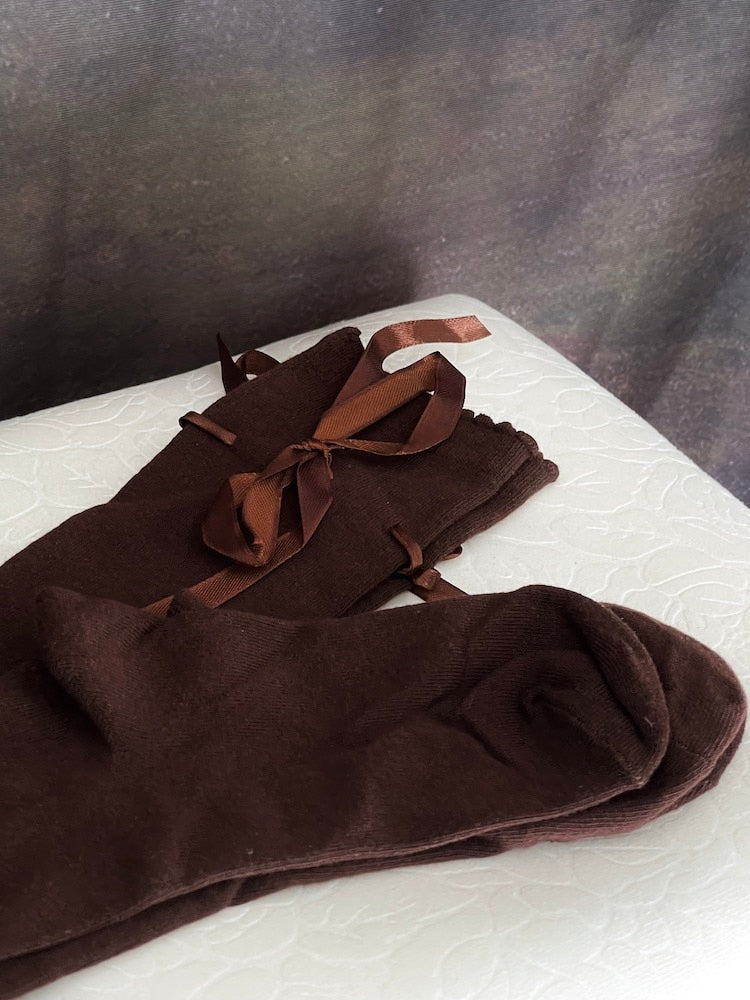 A pair of brown historically inspired knee high stocking socks with ribbon laced bow