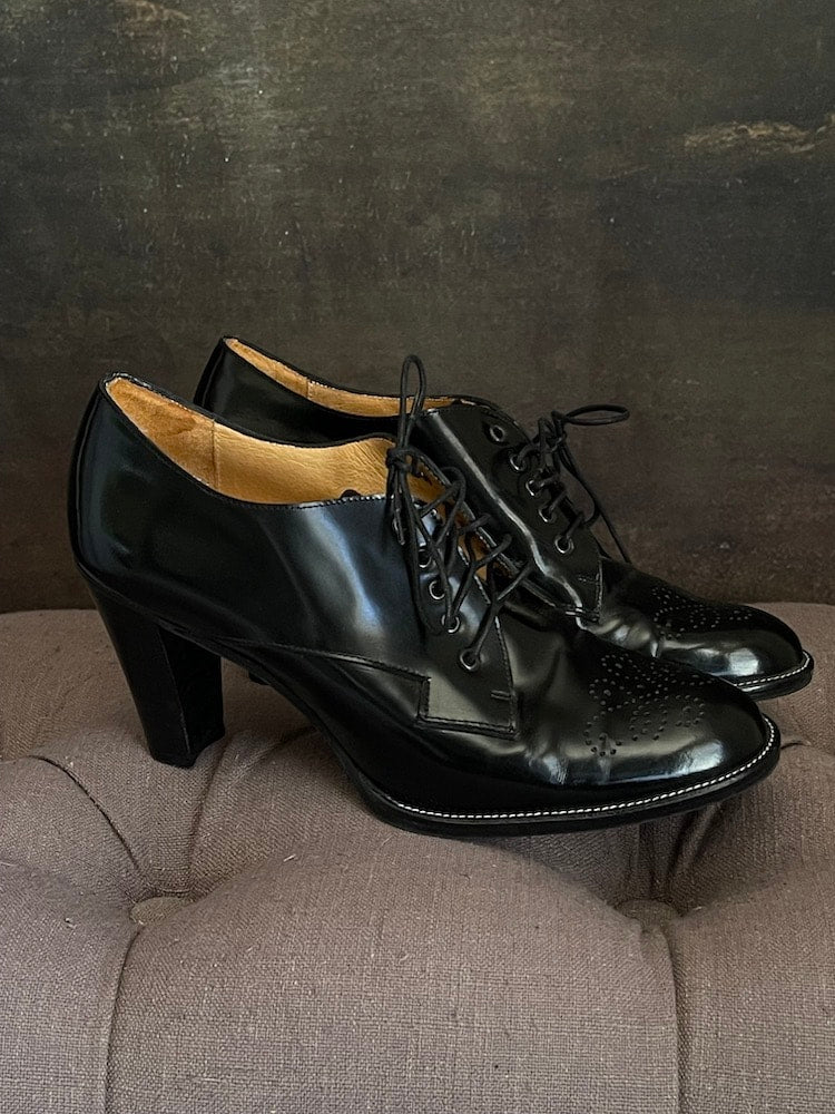 A Pair of historically inspired black patent pleather oxford heels with decretive embossed filigree.   